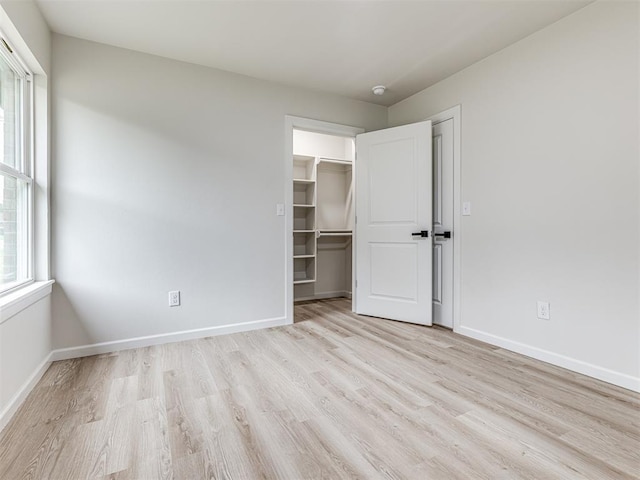 unfurnished bedroom with a walk in closet, light hardwood / wood-style floors, and a closet