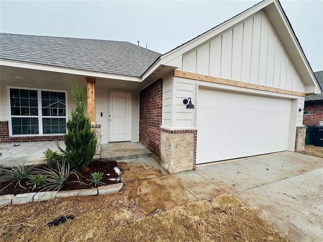 ranch-style home with a garage, brick siding, a shingled roof, concrete driveway, and board and batten siding