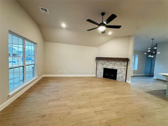 unfurnished living room with vaulted ceiling, a stone fireplace, and light wood-type flooring