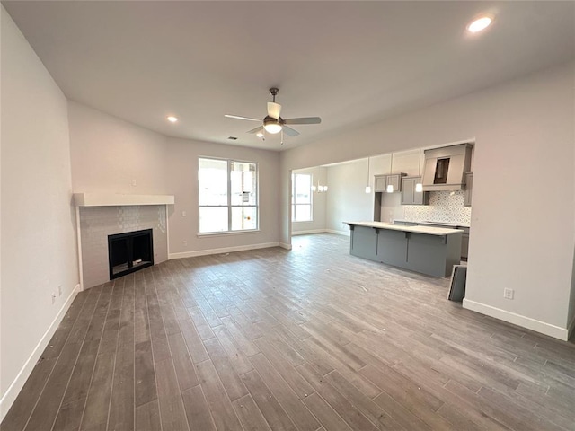 unfurnished living room featuring a fireplace, wood-type flooring, and ceiling fan