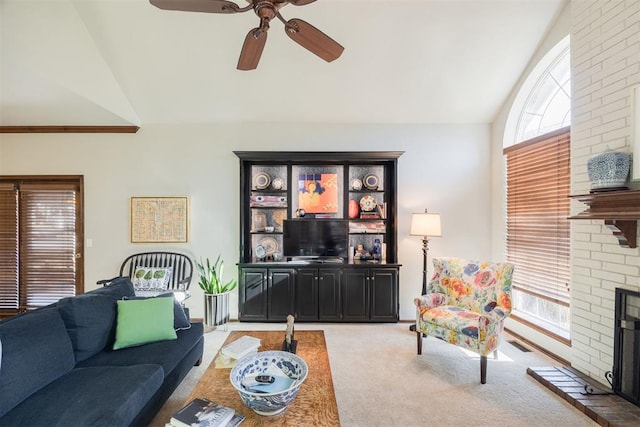 carpeted living room featuring ceiling fan, lofted ceiling, and a brick fireplace