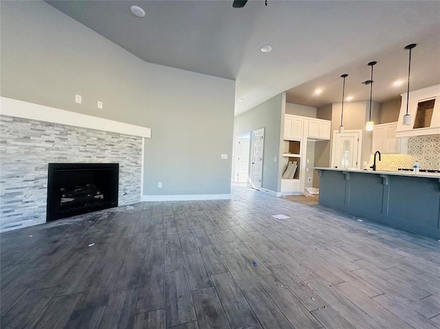 unfurnished living room with sink, ceiling fan, light hardwood / wood-style flooring, and a fireplace