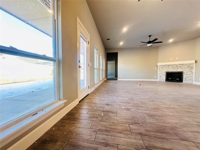 unfurnished living room featuring a ceiling fan, wood finished floors, recessed lighting, a fireplace, and baseboards