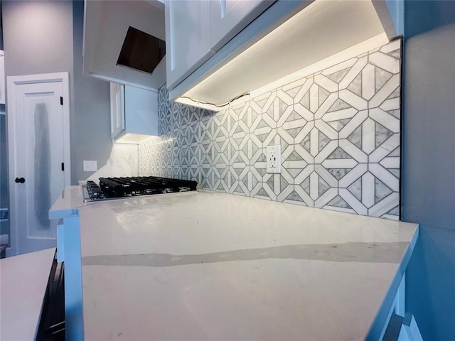 kitchen featuring light stone counters, stainless steel gas cooktop, and decorative backsplash