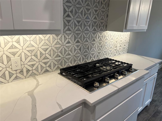 kitchen with light stone countertops, tasteful backsplash, stainless steel gas stovetop, and white cabinets