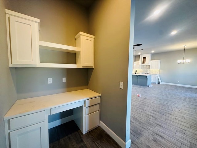 office area with an inviting chandelier, dark wood-style floors, baseboards, and built in study area