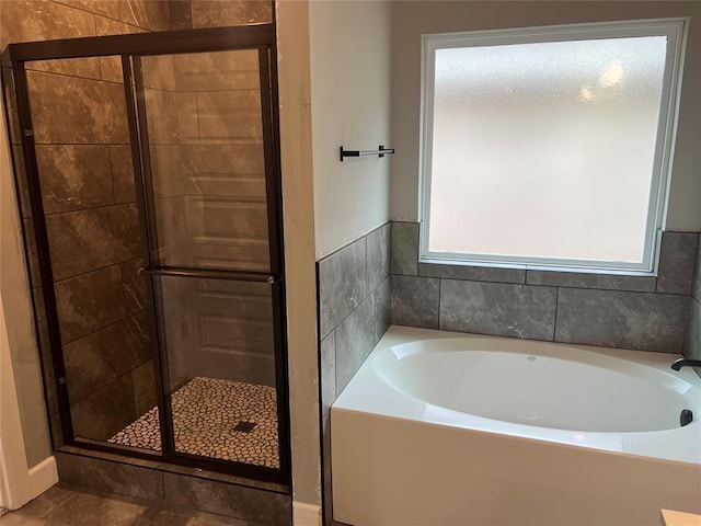 full bathroom featuring a shower stall and a bath