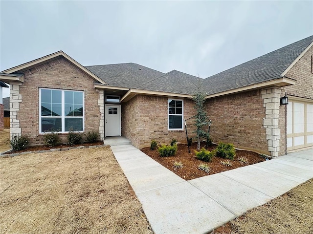 single story home with brick siding, a shingled roof, and a garage