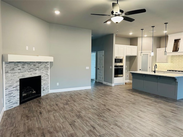 kitchen with open floor plan, decorative backsplash, a fireplace, white cabinets, and stainless steel appliances