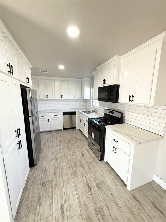 kitchen with white cabinets, light stone counters, sink, and appliances with stainless steel finishes