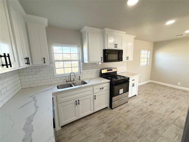 kitchen with tasteful backsplash, light stone counters, sink, white cabinets, and stainless steel range with gas cooktop