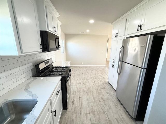 kitchen with white cabinets, light hardwood / wood-style flooring, light stone counters, and black appliances