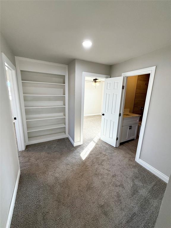 unfurnished bedroom with dark colored carpet and connected bathroom