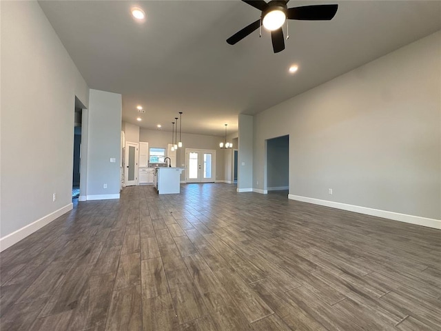 unfurnished living room featuring sink, dark wood-type flooring, and ceiling fan with notable chandelier