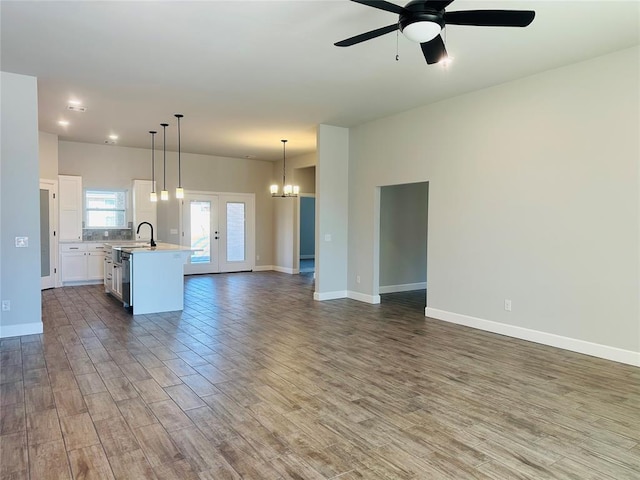 unfurnished living room with sink, dark hardwood / wood-style floors, and ceiling fan with notable chandelier