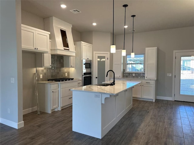 kitchen with white cabinets, sink, and a kitchen island with sink