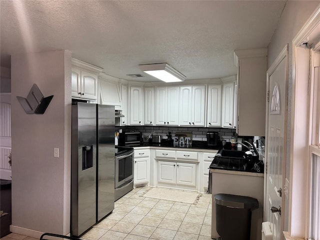 kitchen with appliances with stainless steel finishes, sink, white cabinets, decorative backsplash, and light tile patterned floors