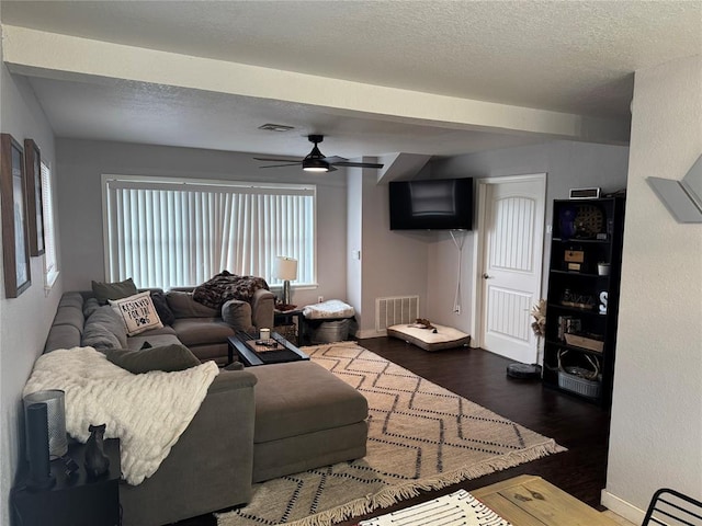 living room with ceiling fan, dark wood-type flooring, and a textured ceiling