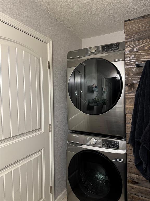 laundry area featuring stacked washer and clothes dryer and a textured ceiling