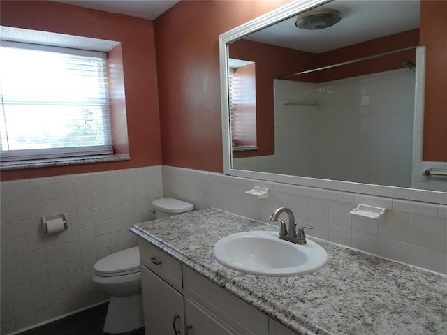 bathroom featuring vanity, tile walls, and toilet