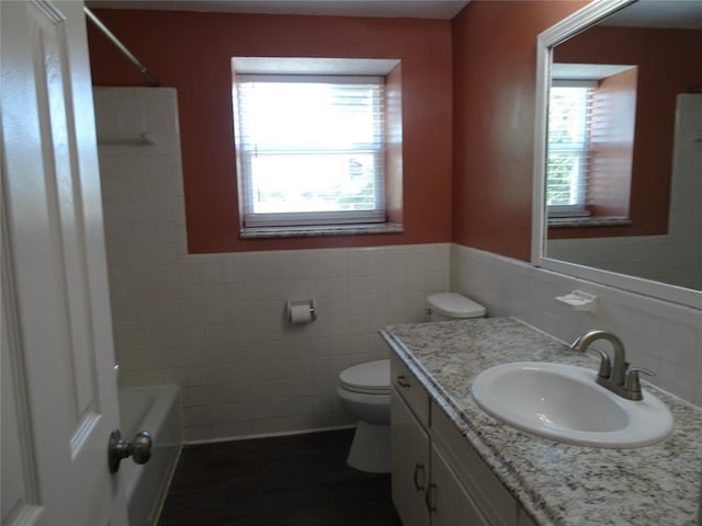 bathroom featuring vanity, plenty of natural light, tile walls, and toilet