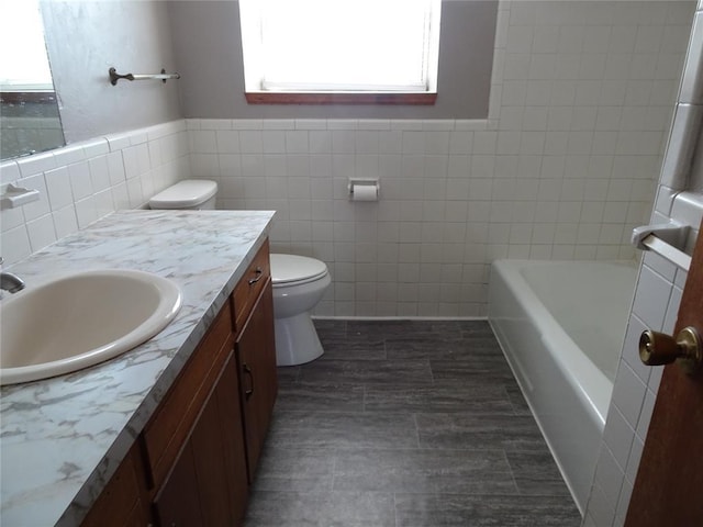 bathroom with vanity, a washtub, tile walls, and toilet