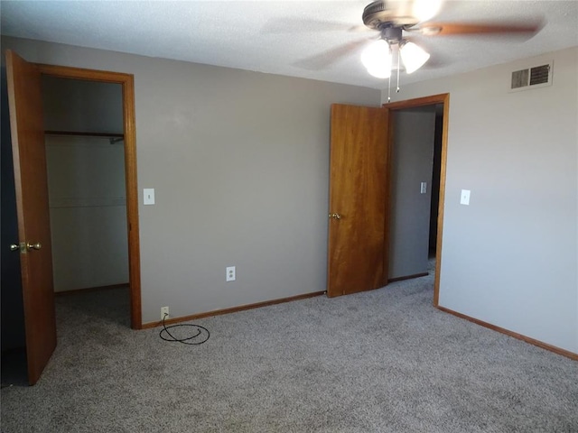 unfurnished bedroom featuring ceiling fan, a spacious closet, carpet floors, and a closet