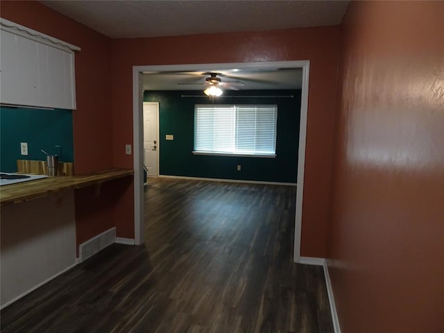 interior space with dark wood-type flooring and ceiling fan