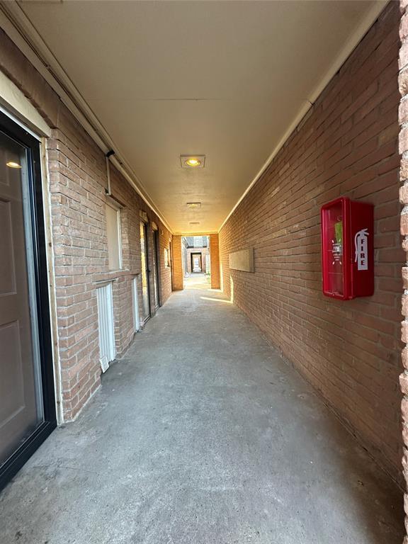 hall with concrete flooring and brick wall