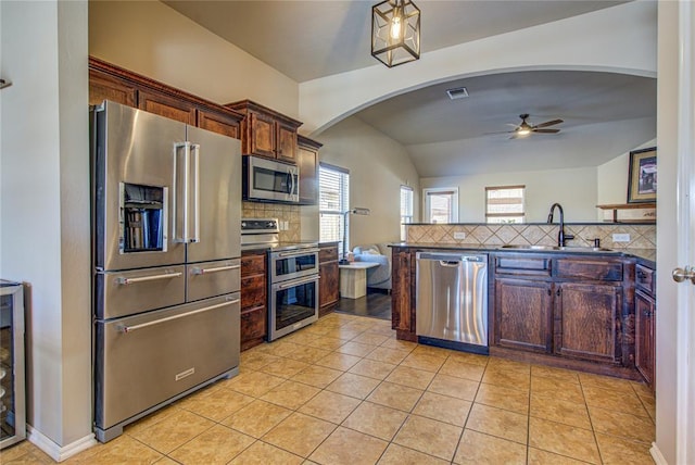 kitchen with stainless steel appliances, sink, lofted ceiling, light tile patterned flooring, and ceiling fan