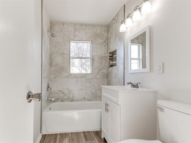 full bathroom featuring toilet, vanity, plenty of natural light, and tiled shower / bath