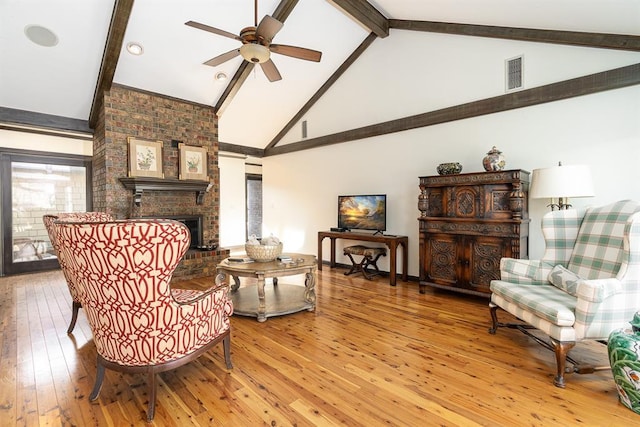 sitting room with beam ceiling, ceiling fan, a brick fireplace, high vaulted ceiling, and hardwood / wood-style flooring