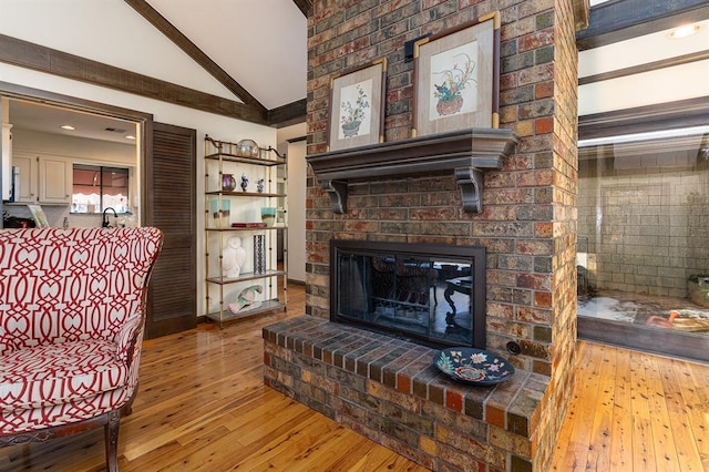 living room with a fireplace, light hardwood / wood-style floors, high vaulted ceiling, and sink