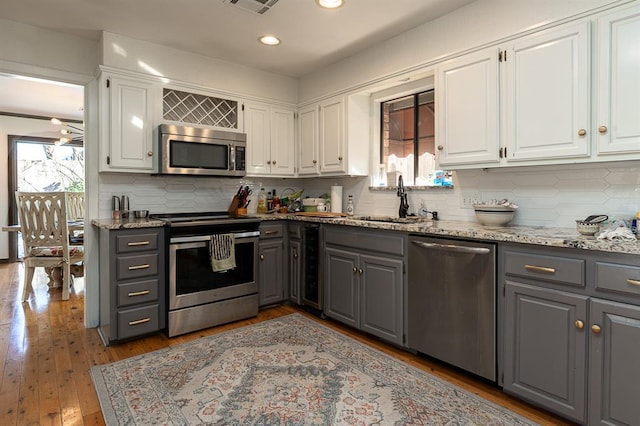 kitchen featuring appliances with stainless steel finishes, a wealth of natural light, gray cabinetry, sink, and white cabinets