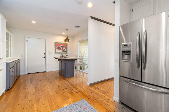 kitchen featuring a kitchen bar, stainless steel fridge with ice dispenser, light wood-type flooring, and white cabinetry