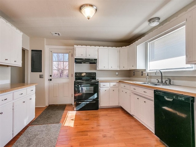 kitchen with electric panel, light hardwood / wood-style floors, black appliances, white cabinets, and sink