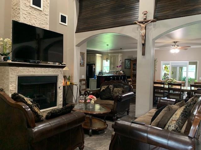 living room with a fireplace, ceiling fan, and crown molding