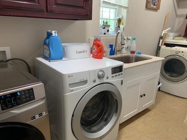 laundry room with sink, cabinets, light tile patterned flooring, and washing machine and clothes dryer