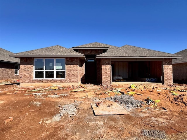 view of front of home featuring a garage, brick siding, and a shingled roof