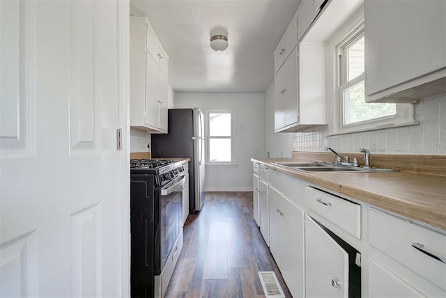 kitchen with a wealth of natural light, white cabinets, stainless steel gas range oven, and sink