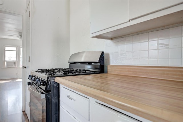 kitchen featuring ceiling fan, wooden counters, white cabinetry, cooling unit, and gas range