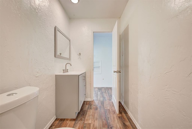 bathroom with hardwood / wood-style floors, toilet, and vanity