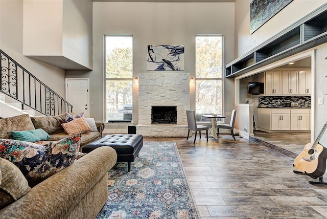 living room with wood-type flooring, a fireplace, and a high ceiling