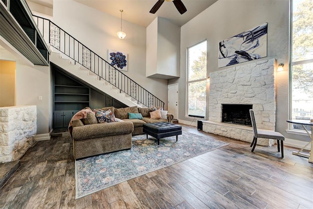 living room with hardwood / wood-style flooring, a healthy amount of sunlight, a fireplace, and a high ceiling