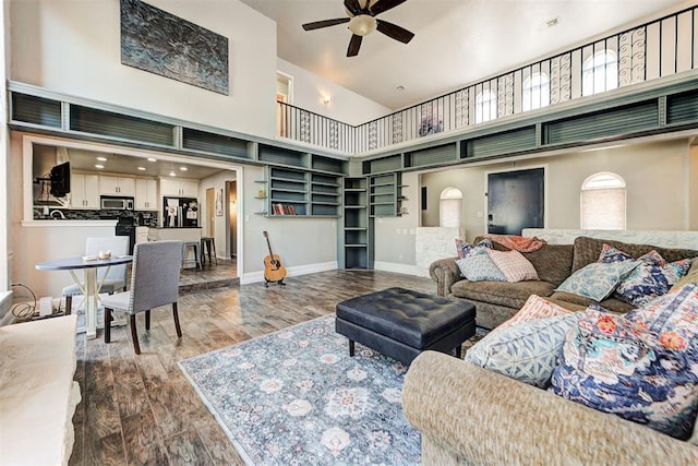 living room featuring hardwood / wood-style flooring, a towering ceiling, and ceiling fan