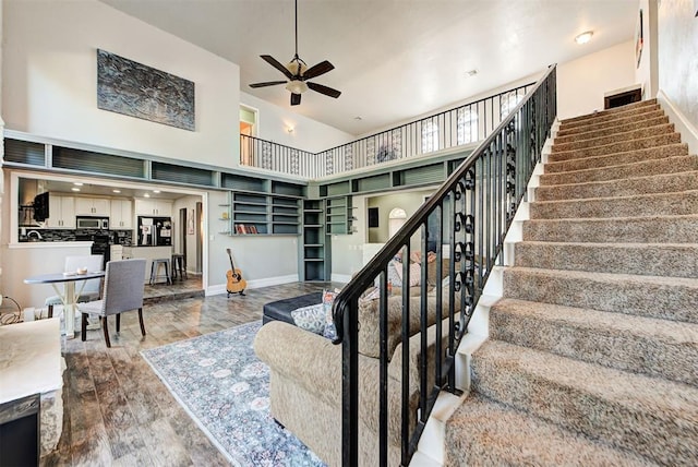 living room featuring a towering ceiling, ceiling fan, and hardwood / wood-style flooring