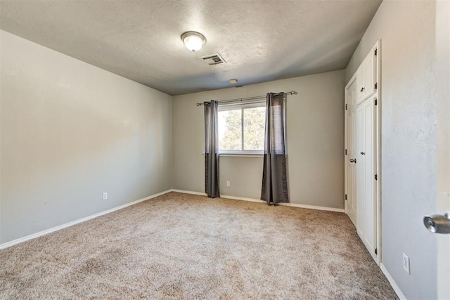 spare room with light carpet and a textured ceiling