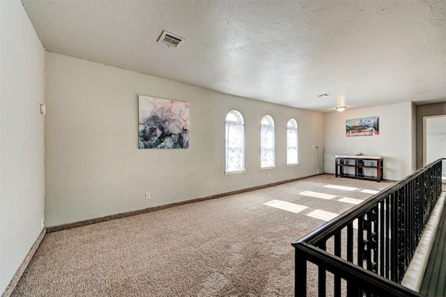 carpeted empty room featuring a textured ceiling