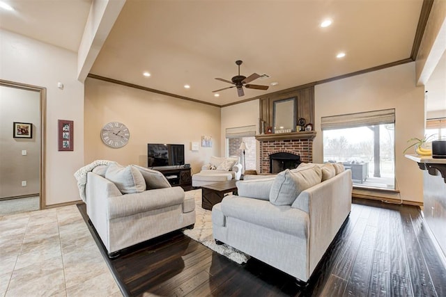 living room featuring a brick fireplace, a ceiling fan, crown molding, and recessed lighting