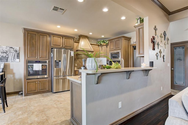 kitchen featuring visible vents, decorative backsplash, a peninsula, a breakfast bar, and appliances with stainless steel finishes